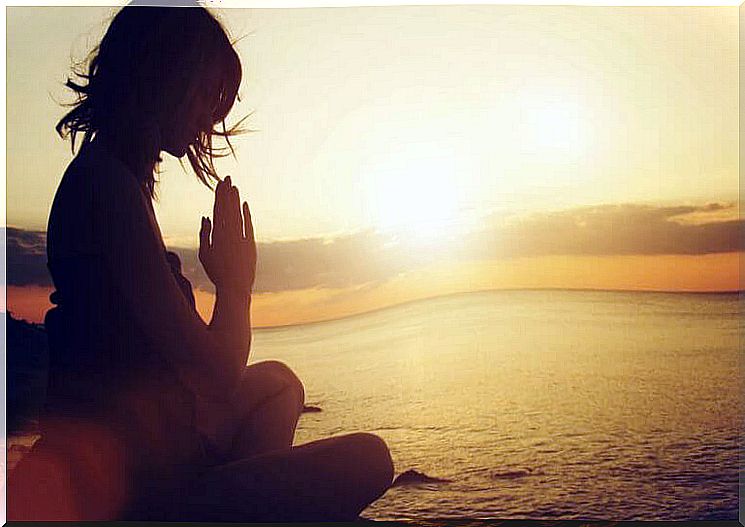 Woman meditating at sunset.