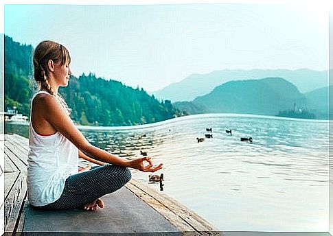 Woman meditating on the edge of a lake.