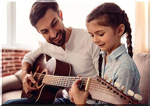 father playing guitar with his daughter