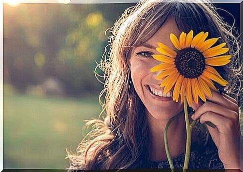 Woman with sunflower hiding part of her face.